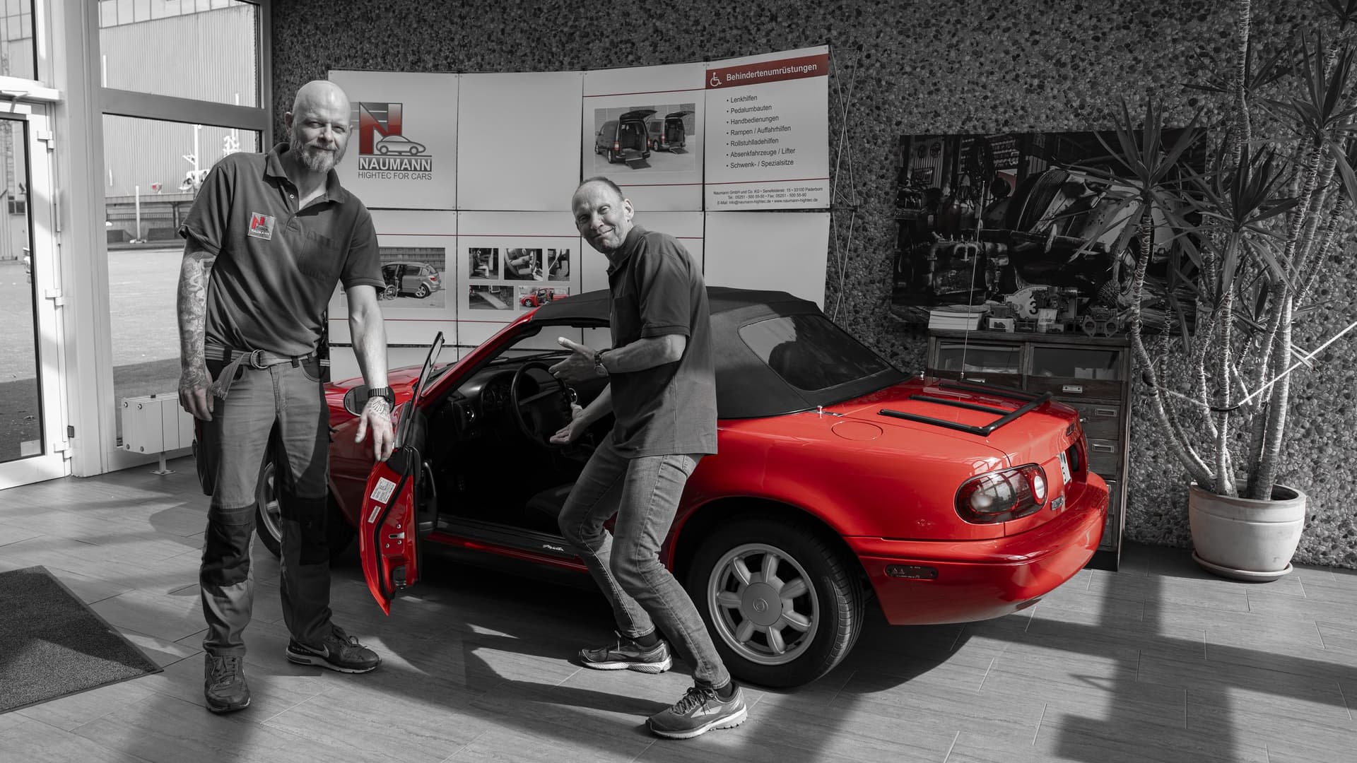 Team von Naumann Hightec am roten Mazda MX-5 Oldtimer im Showroom